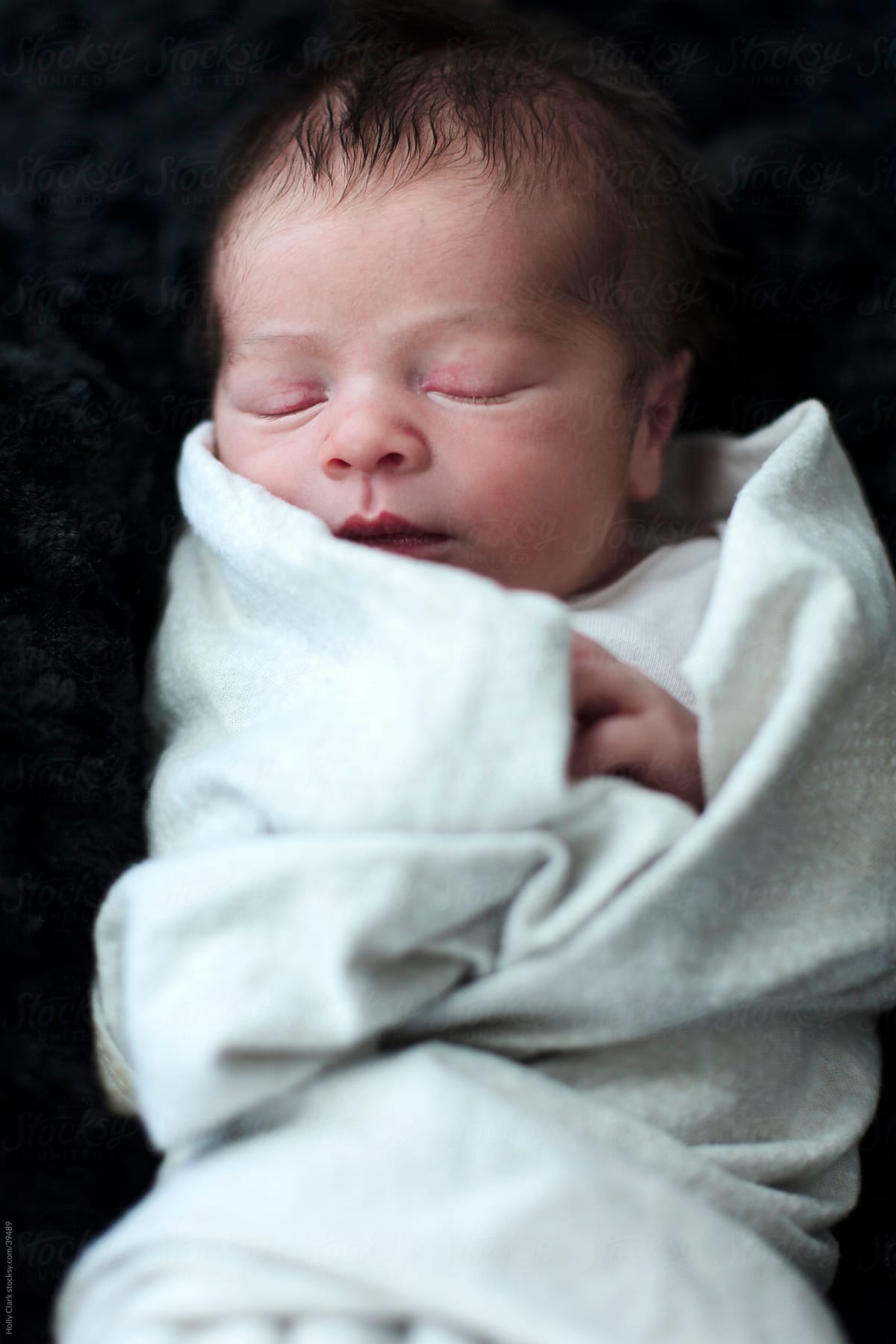 Swaddled Newborn Sleeping on Black Background