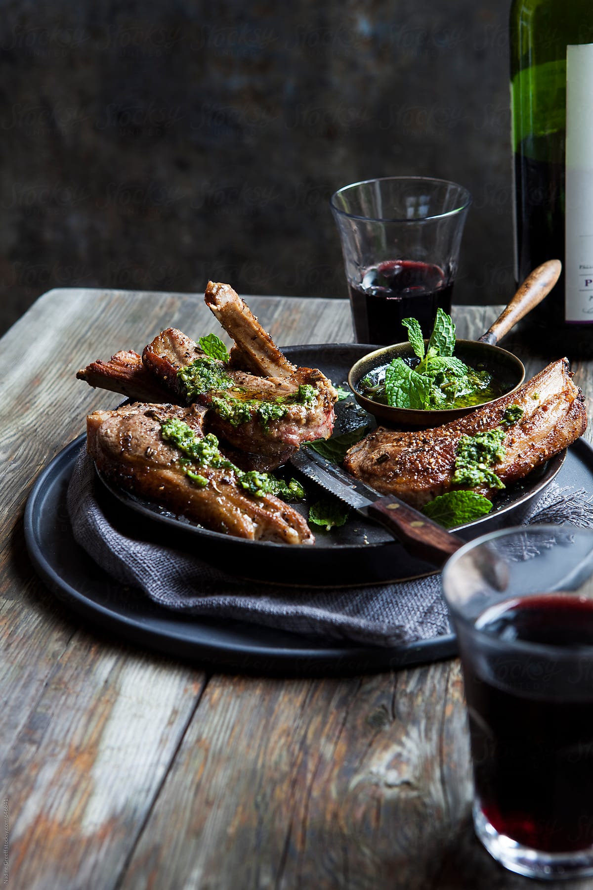 Meat lamb chops with chimichurri sauce and glasses of red wine