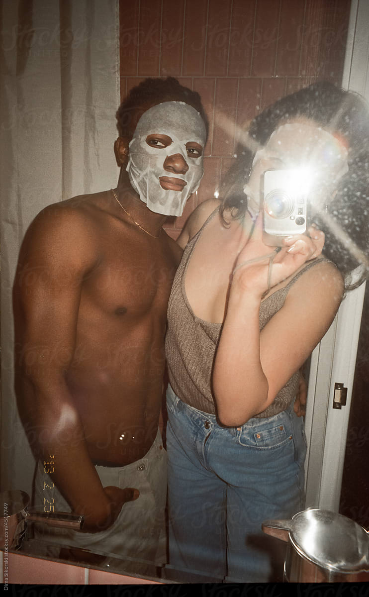 A couple in love with a fabric cosmetic mask take a selfie