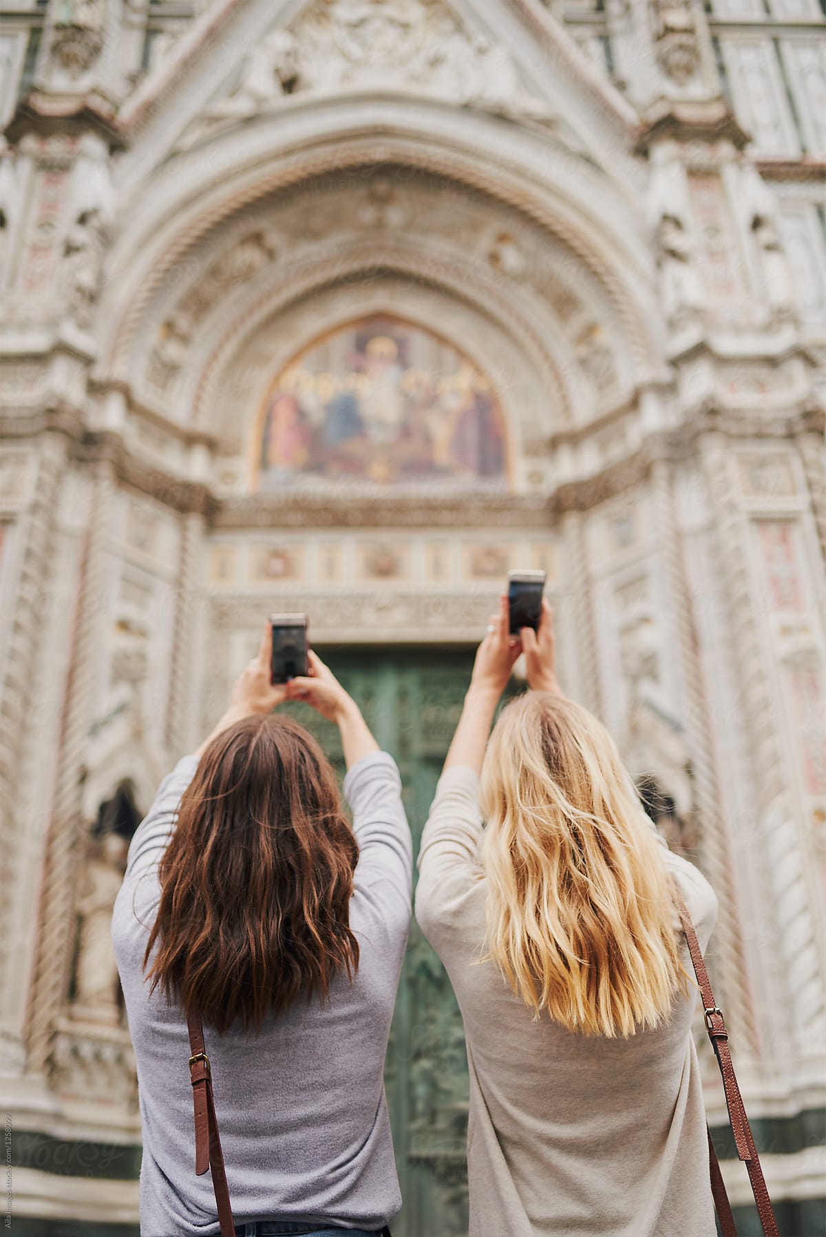 Two girl friends photograph architecture buildings with smart ph