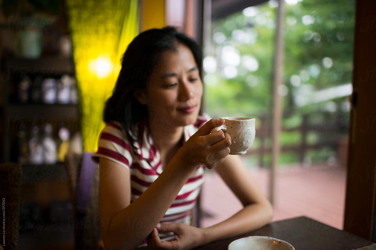 Pretty woman enjoying coffee by the widow in cafe.