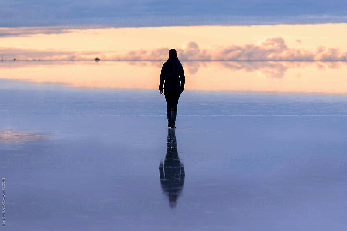 Reflection of a woman walking in Uyuni\'s salt flat in Bolivia