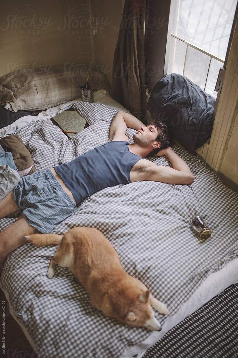 Man Resting in Bed at Home with Dog