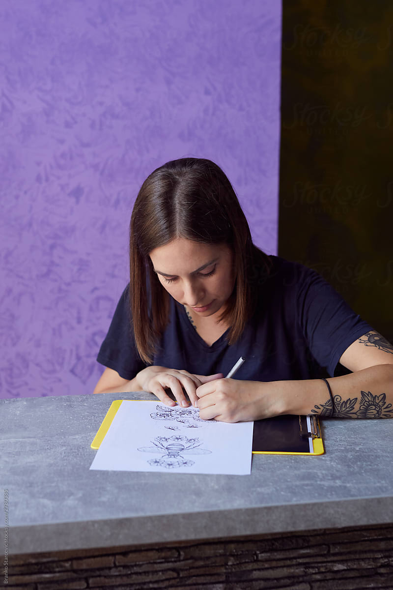 Young woman drawing a tattoo on the paper.