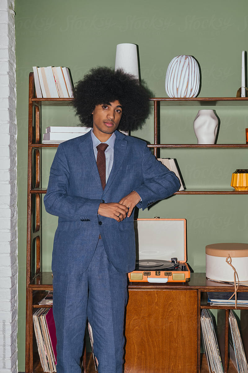 Young businessman with afro style hair  near shelf with vinyl player