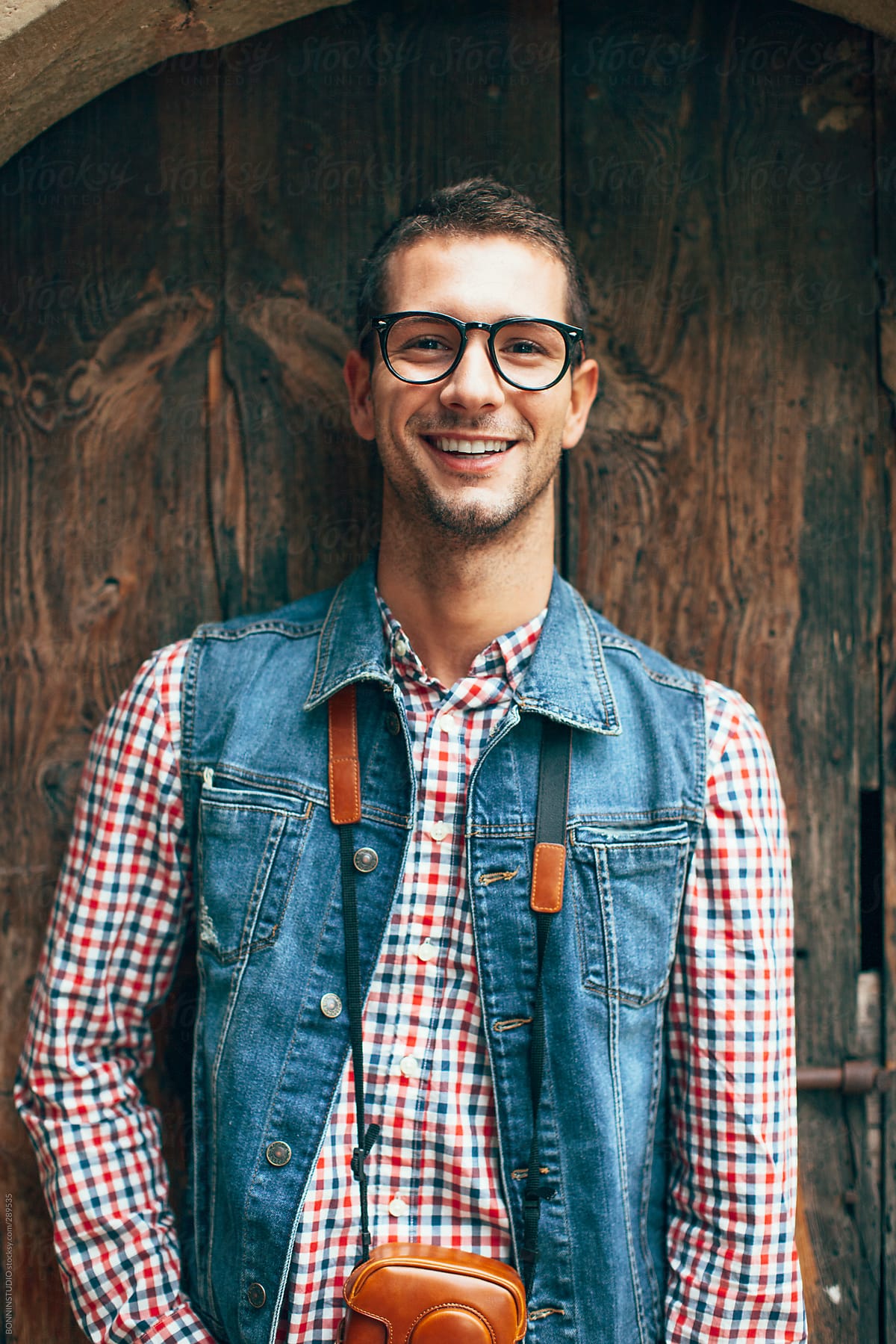 Portrait of a young  smiling man in front a old wooden door.