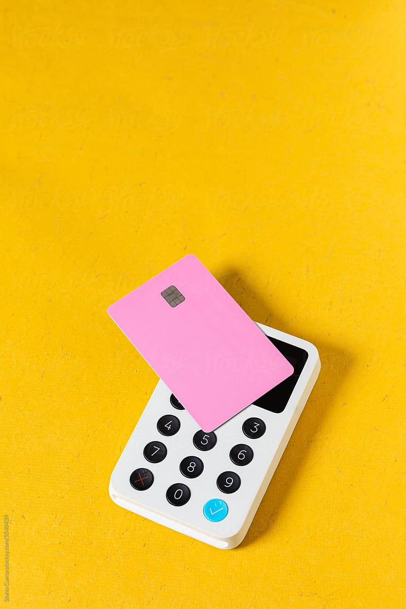 A pink credit card on a white wireless terminal payment