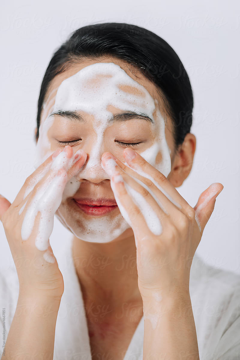 Woman happy cleanses the skin with foam