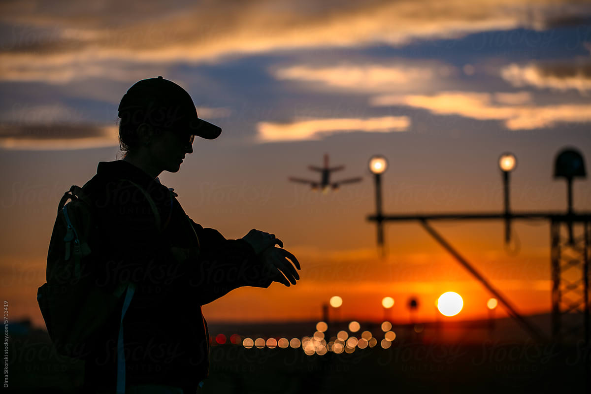 Silhouette of a hurrying traveler with a plane and a sunset airport