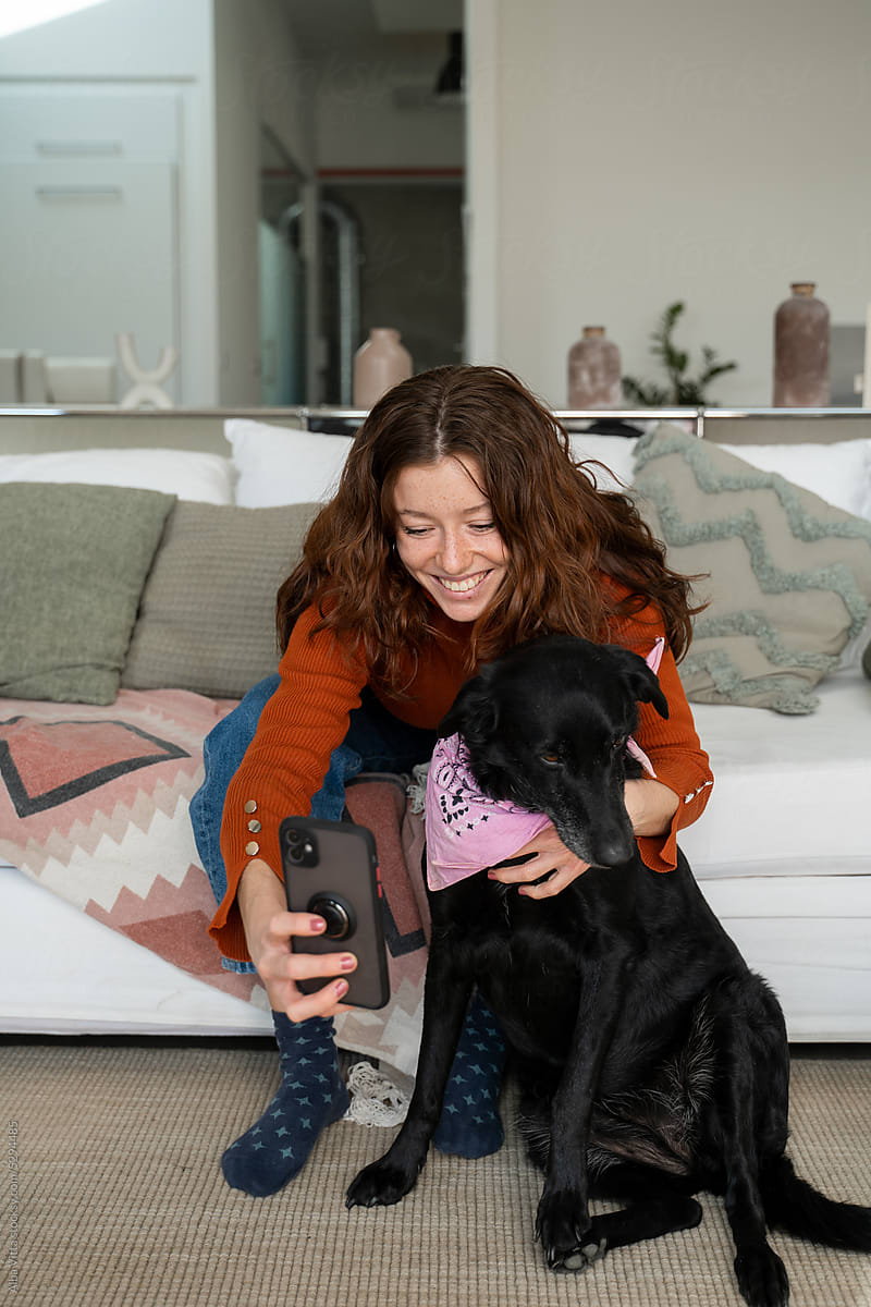 Woman taking selfie with dog at home