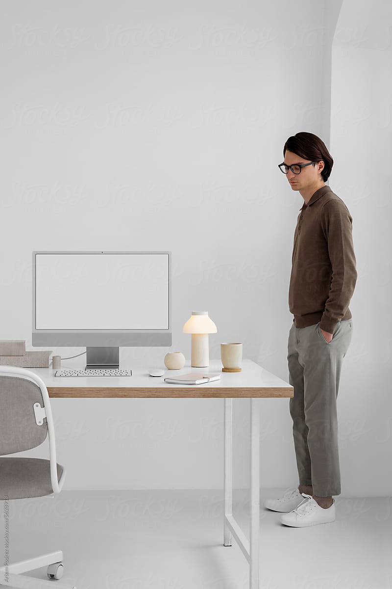 A young man in a office near a computer. White computer screen, mockup