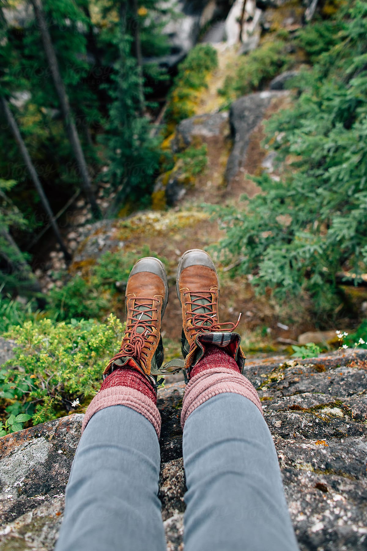 Feet dangling off the edge of a cliff outdoors in nature