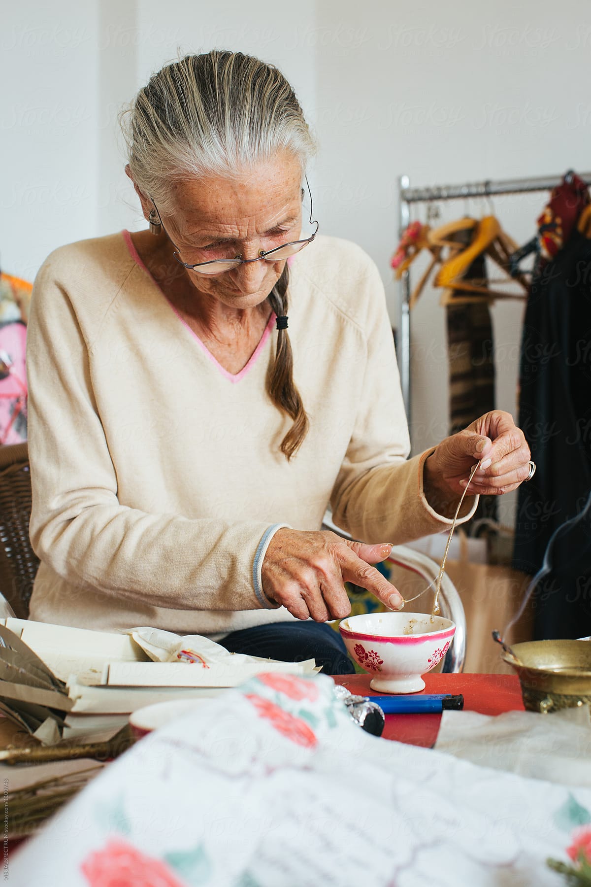 Environmental Portrait of Senior Woman with Grey Hair Making Natural Incense Stick