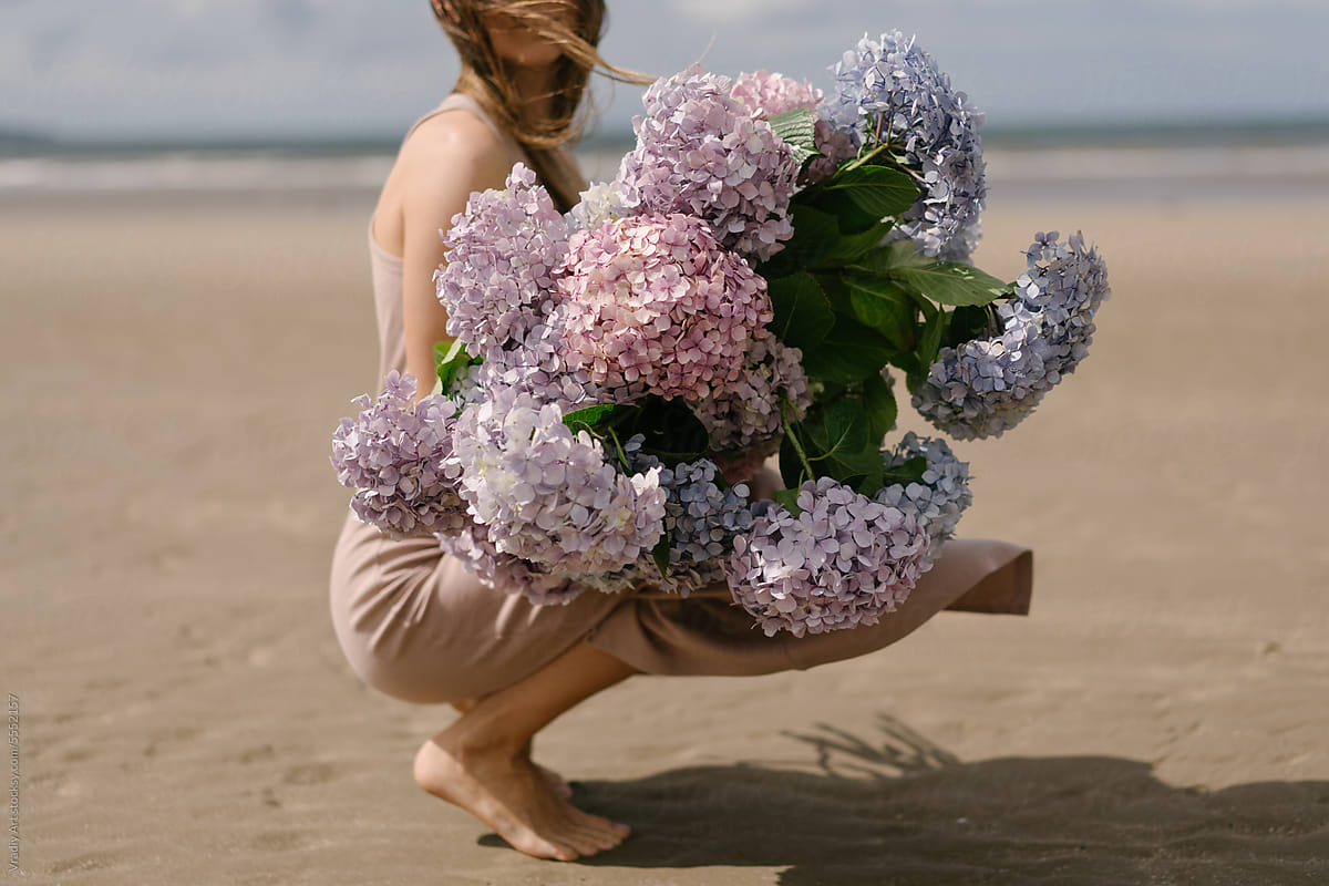 Woman with beautiful bouquet of flowers on the beach