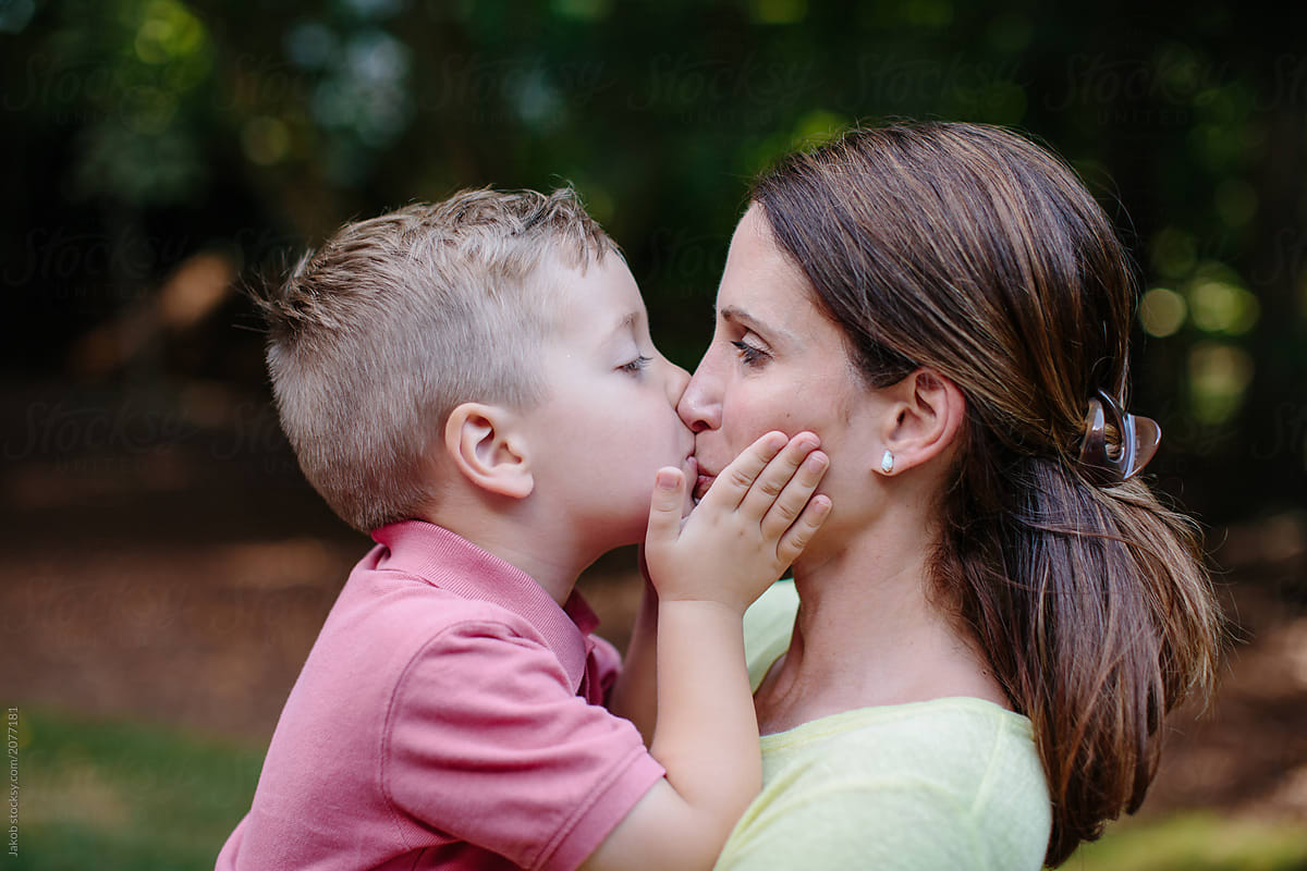 Cute Young Boy Giving His Mother An Affectionate Kiss On The Mouth By
