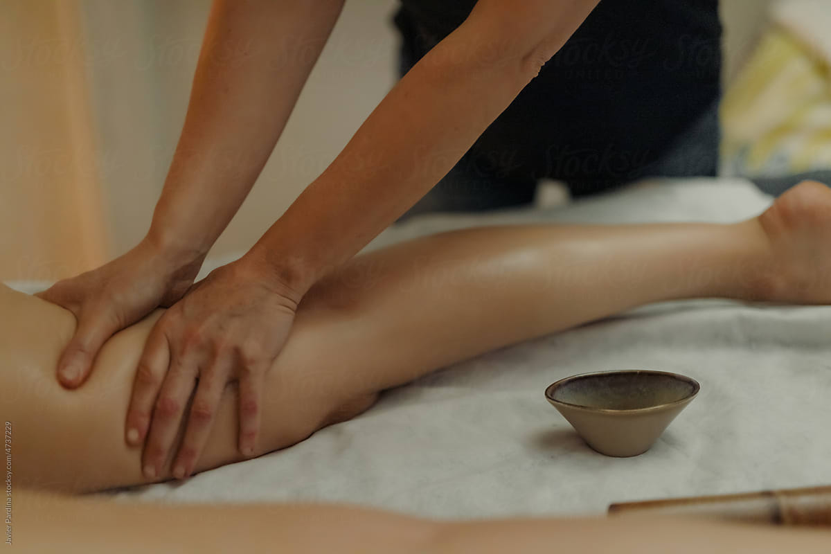 Hands massaging female legs with bamboo