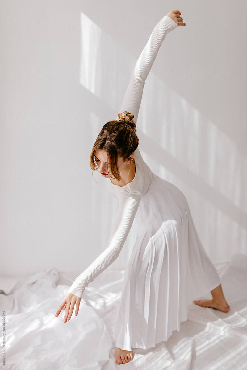 Woman in white dress dancing in light room