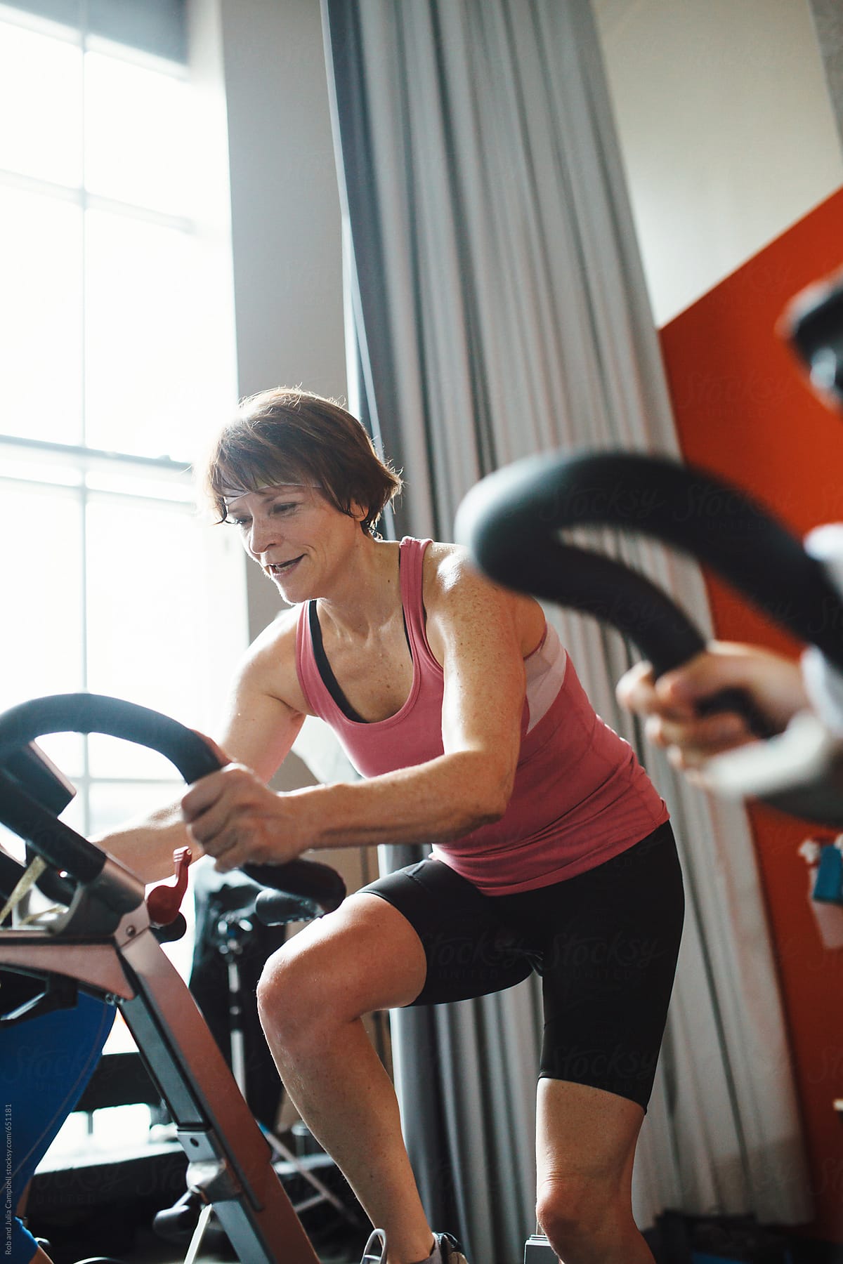 Happy middlle aged woman enjoying working hard during spin cycle class