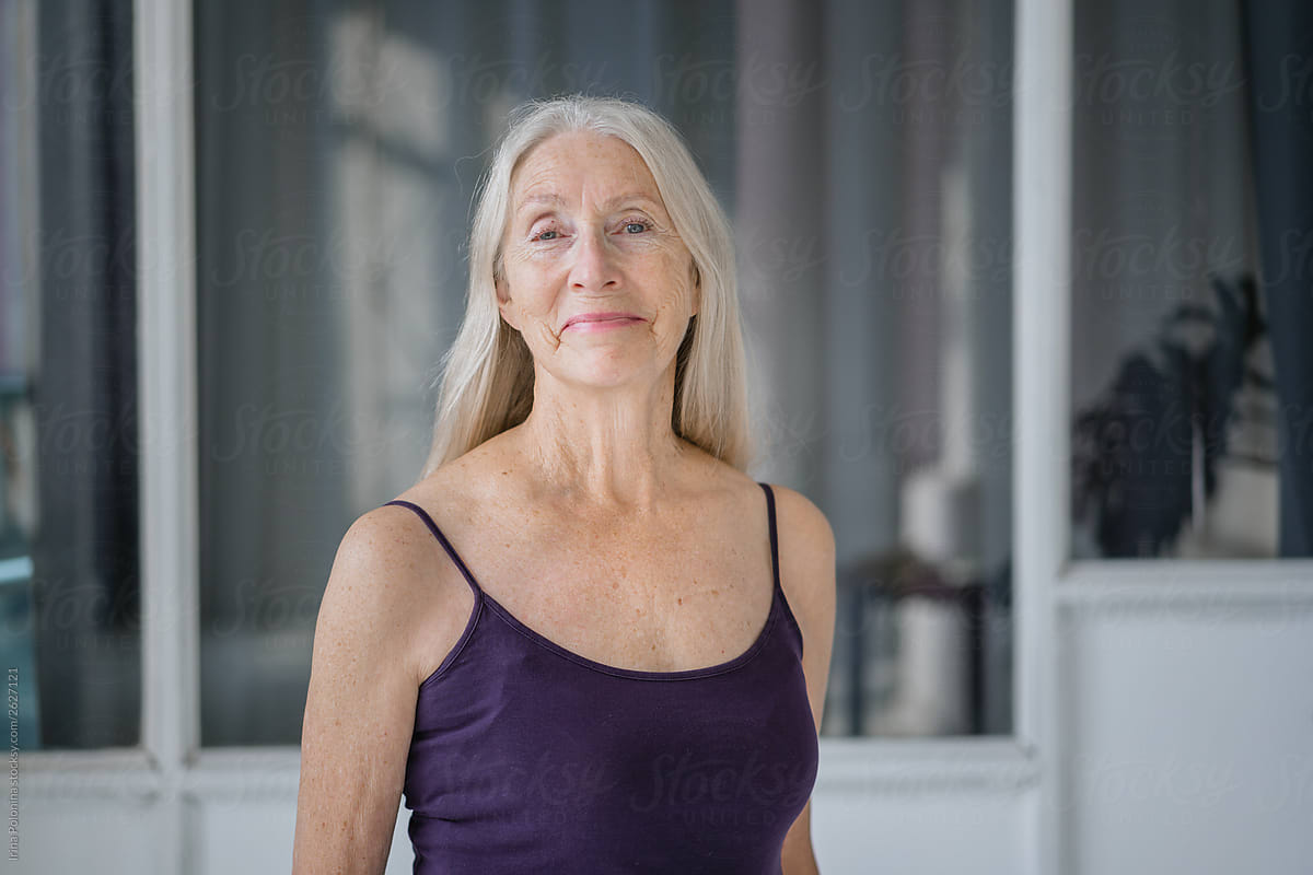 Portrait Of A Senior Woman With Grey Long Hair In White Modern Studio By Stocksy Contributor