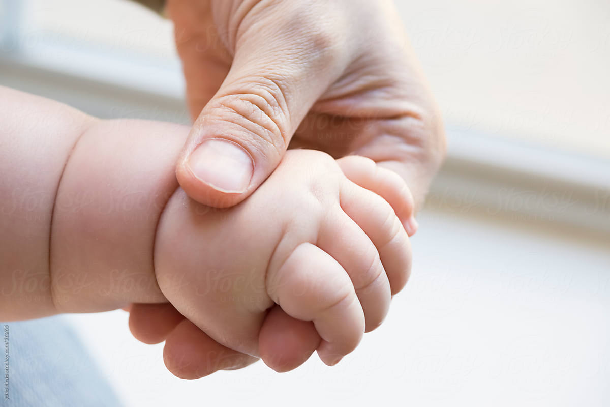 Baby, holding mother's hand indoors
