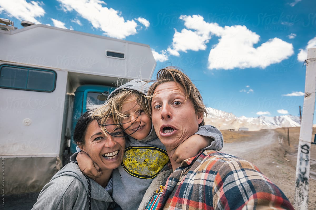 funny and happy faces of a family reaching the highest point of the pamir highway with their camping truck in the back