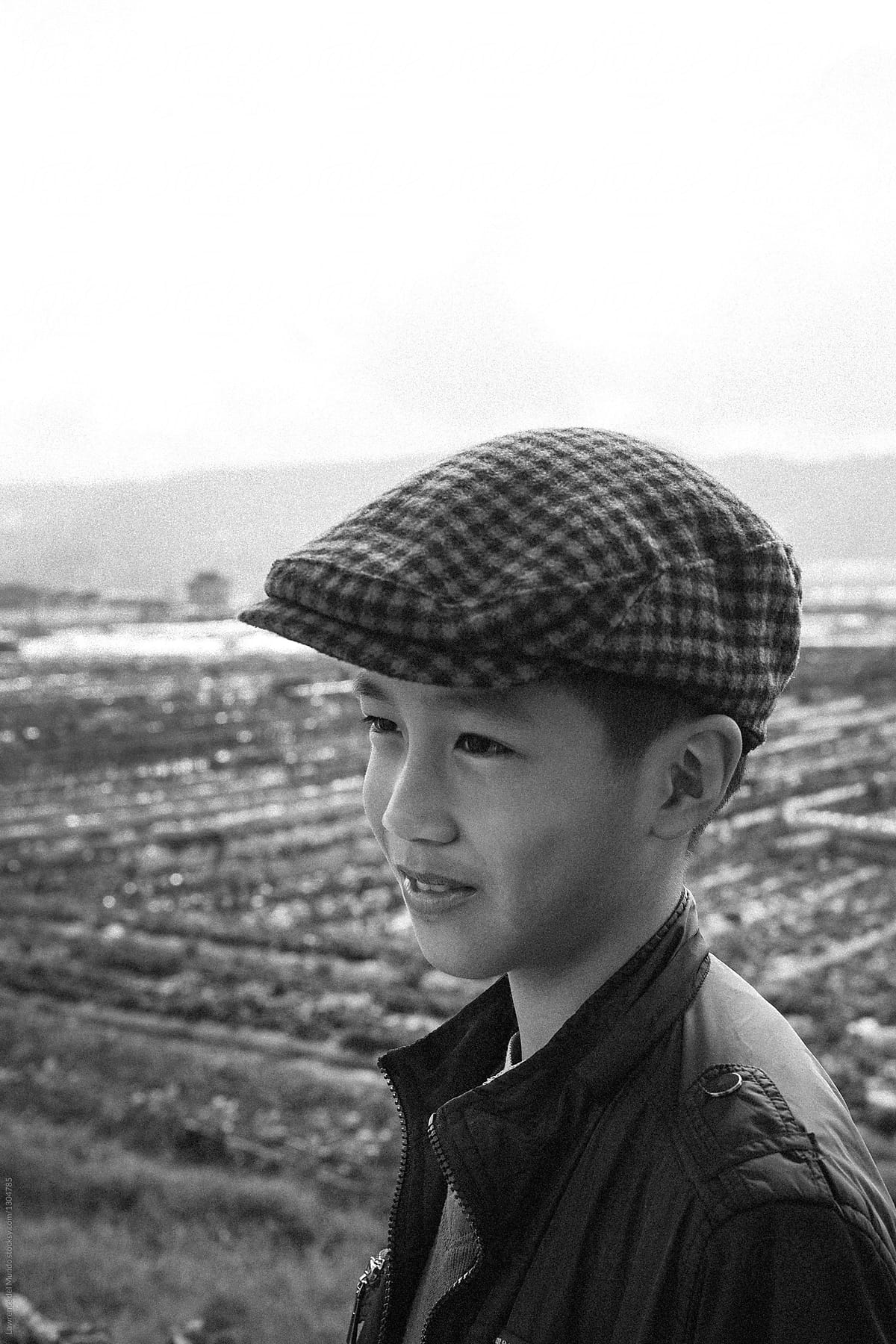 Black and white portrait of a young boy smiling but looking away from the camera.