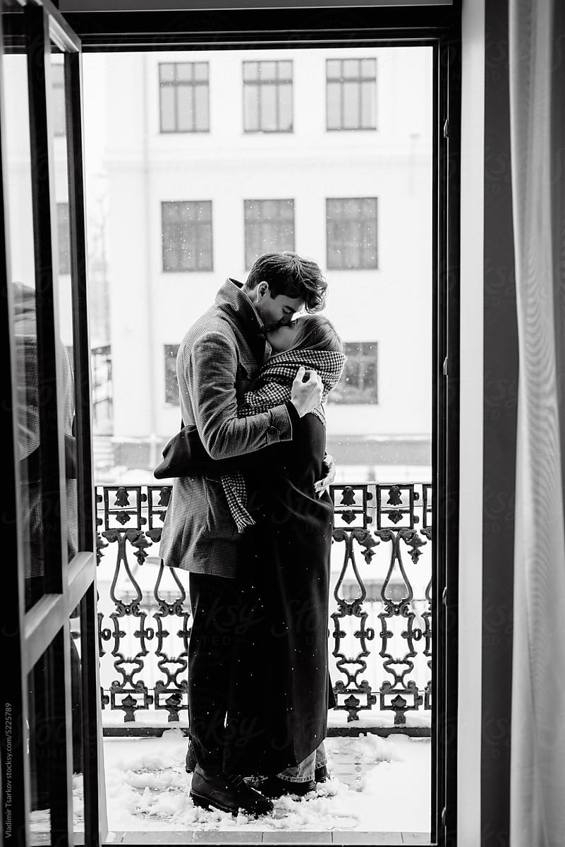 Romantic couple hugging and kissing on balcony in hotel