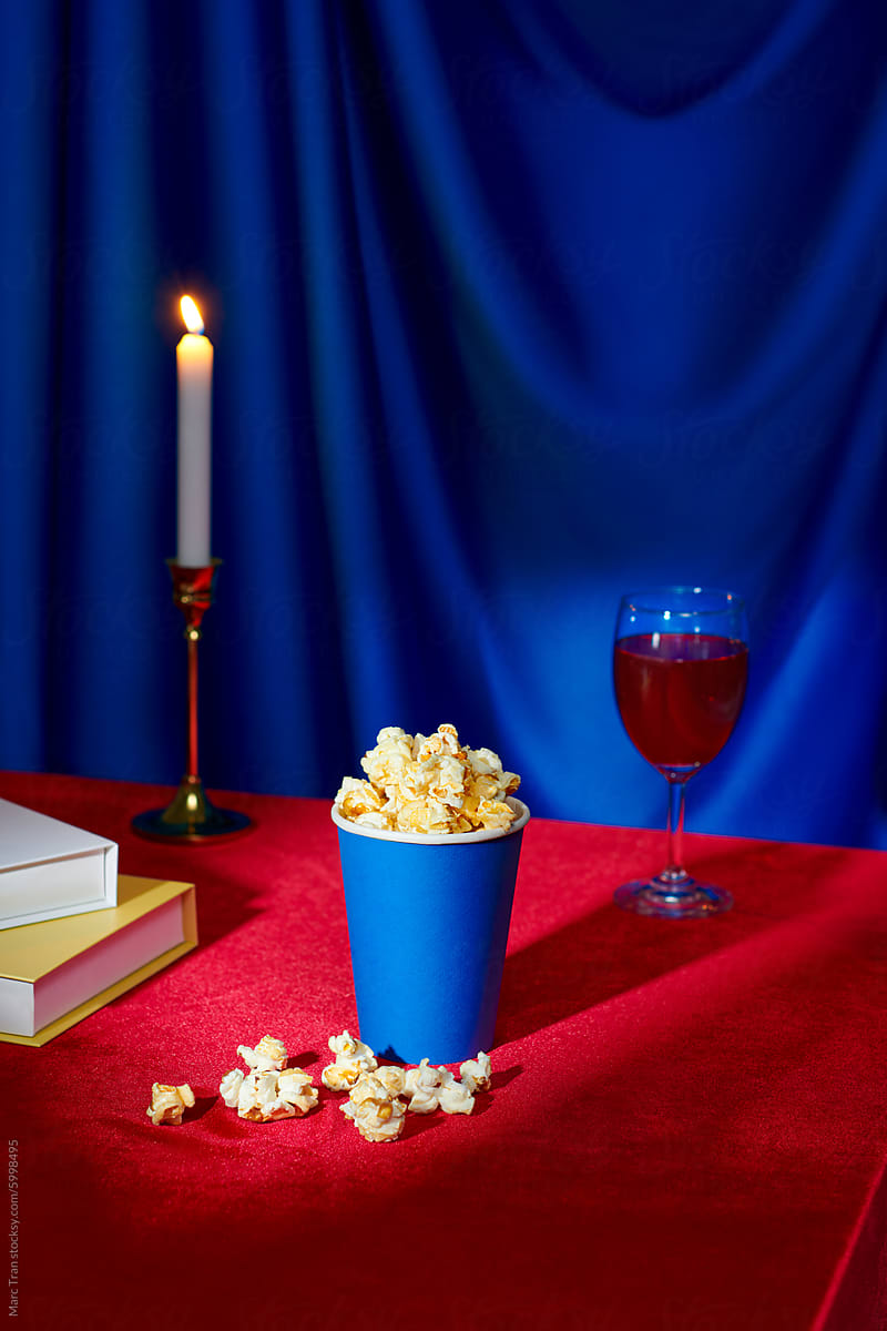 a bag of fresh popcorn with soft drink on red table over blue