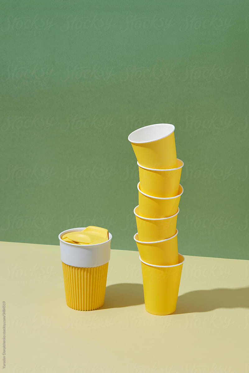 One reusable mug and stack of paper disposable cups.