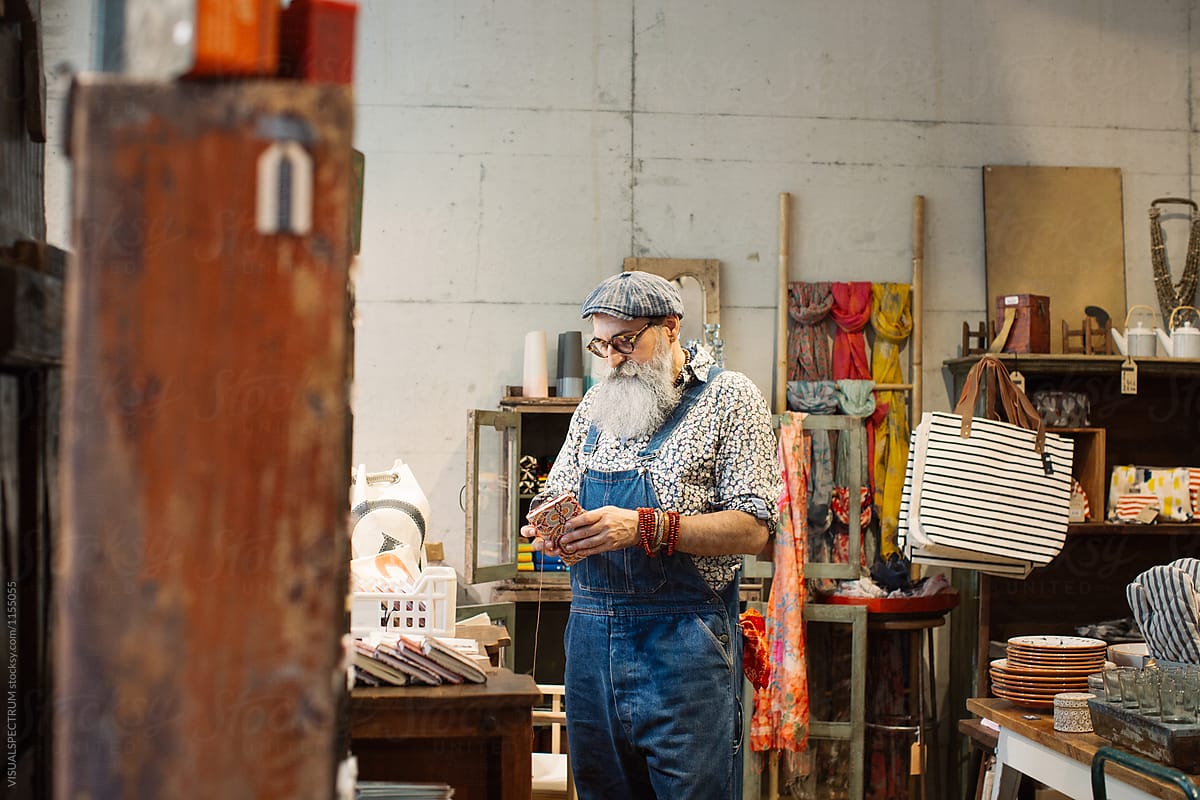 Elderly Fashionable Hipster Looking at Artisan Notebook in Cute Shop