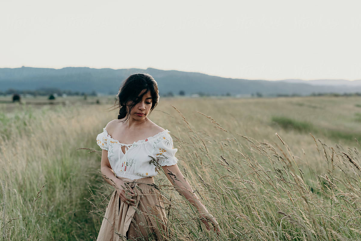 Dark Haired woman standing in a tall grassland path at Sunset near Portland Oregon