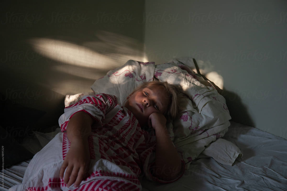 Girl rests against a blanket as the setting sun throws light.