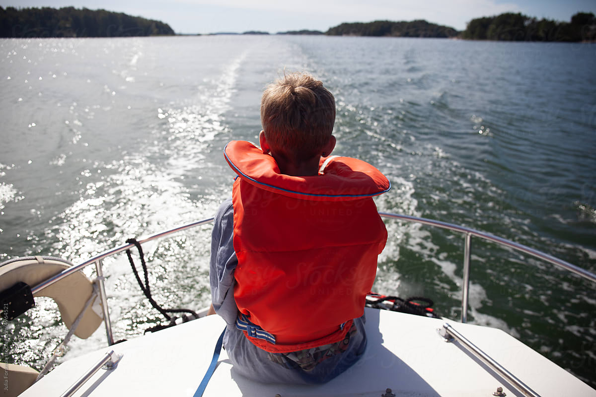 Teen boy looks out over water and islands as he sails