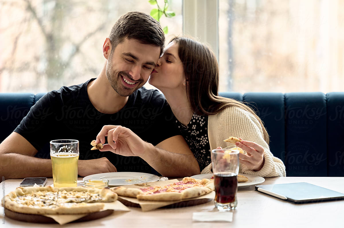 Couple eating pizza and smiling.