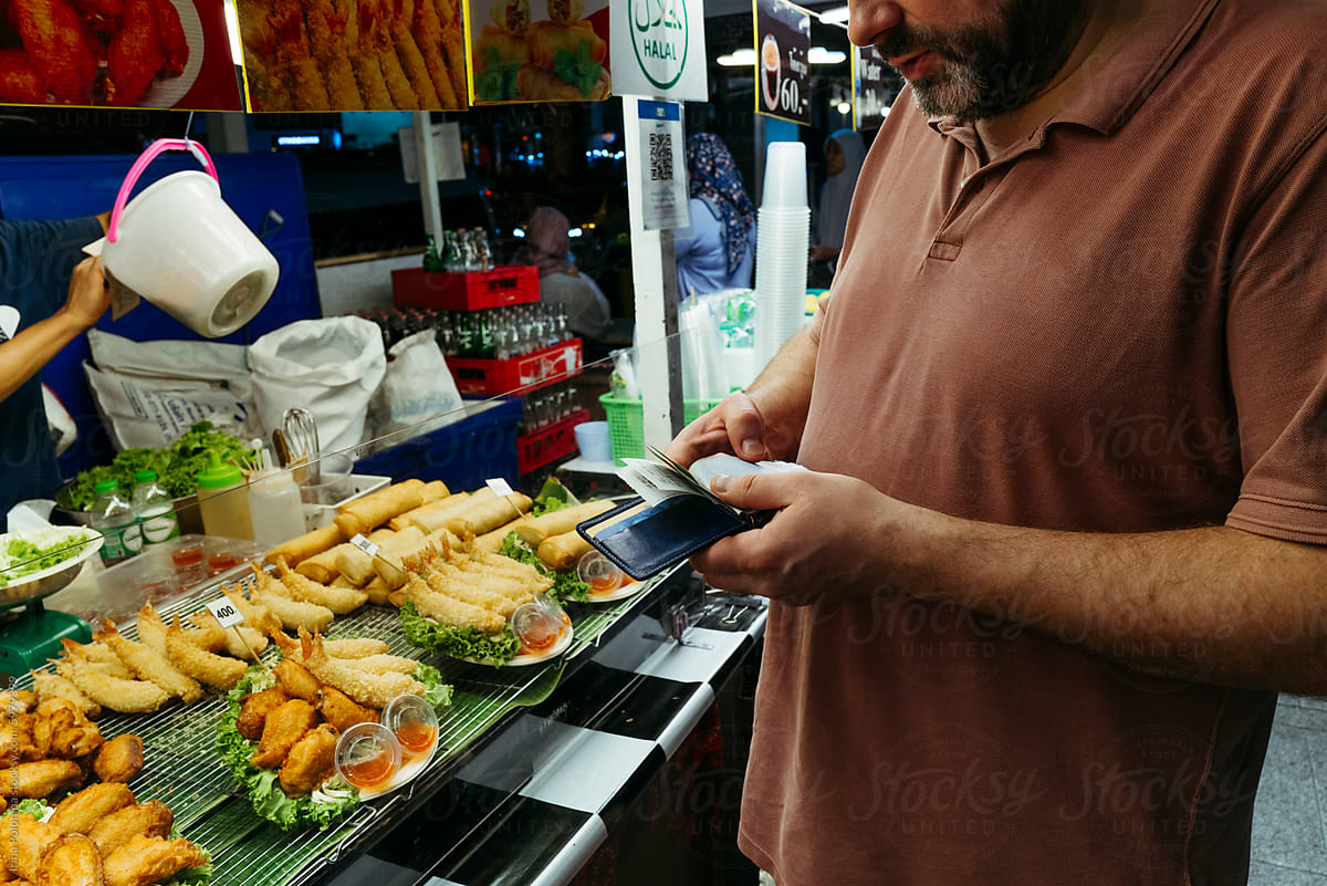 Man Paying at Street Food Stall at Night