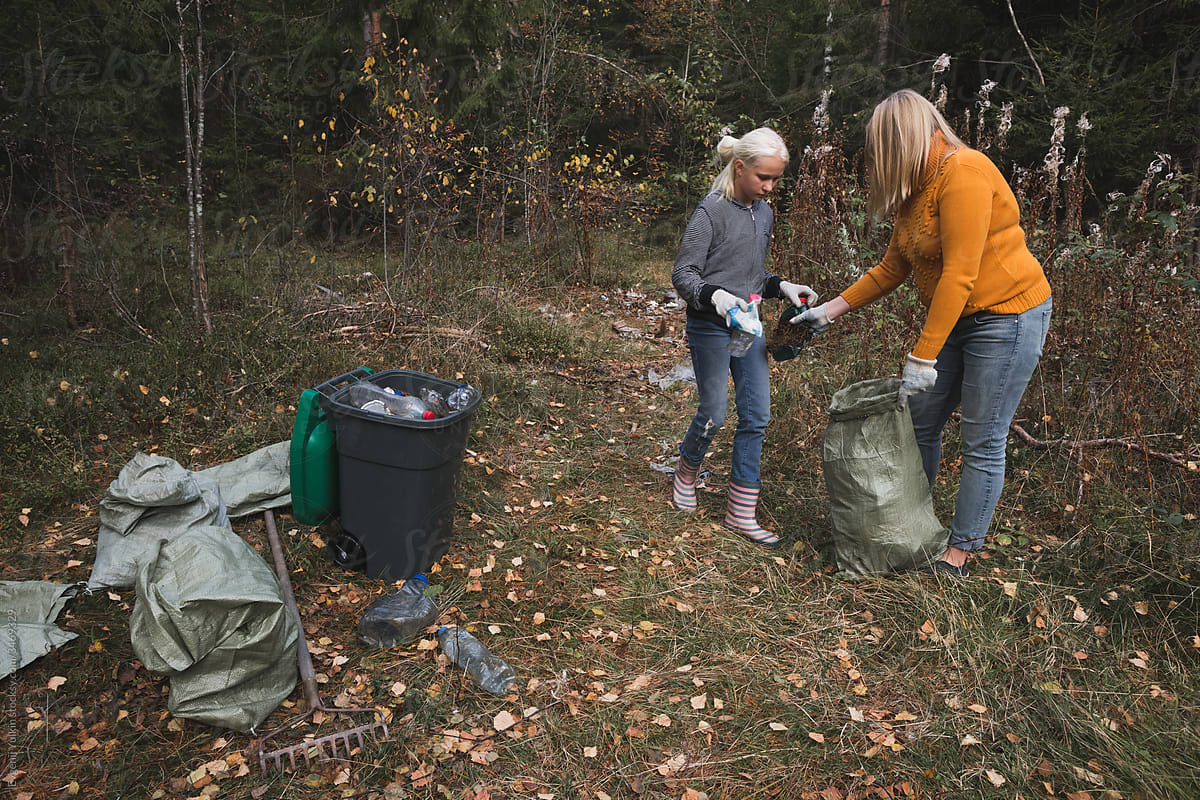 Woman and her daughter collect plastic litter in the forest