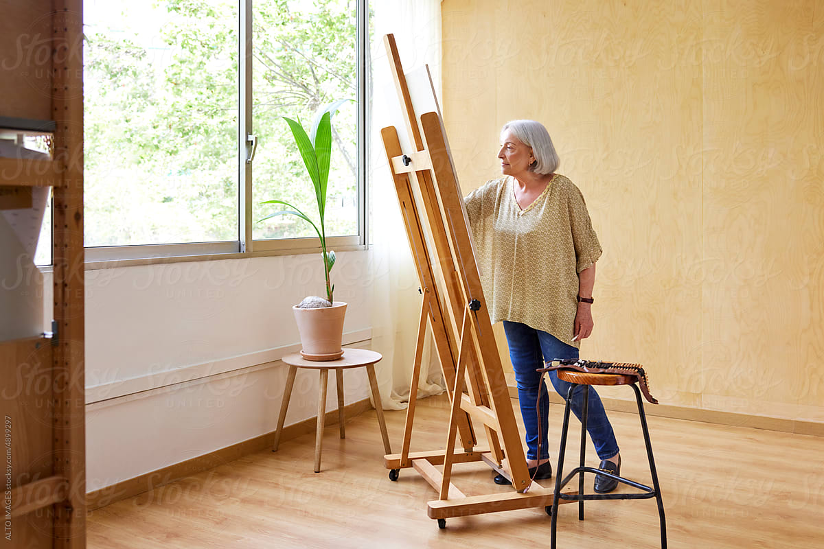 Aged artist working in sunlit studio