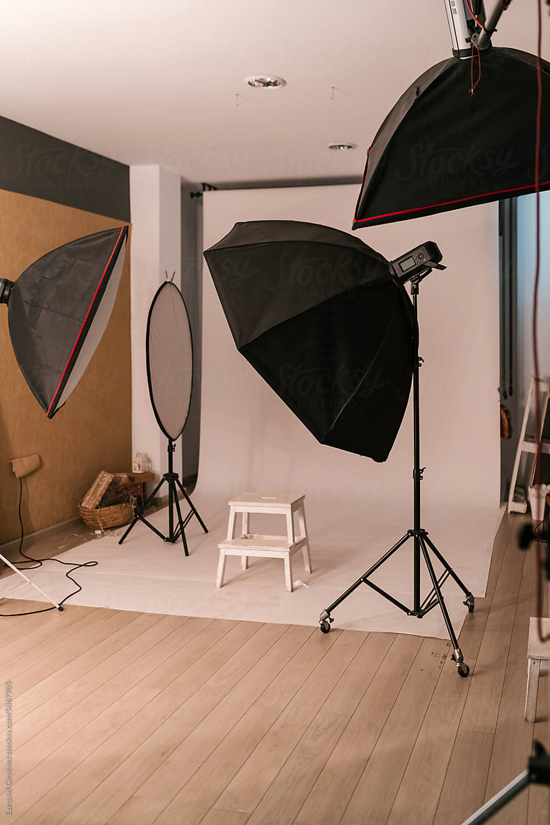 Modern photographic studio with umbrella flash lights and stool