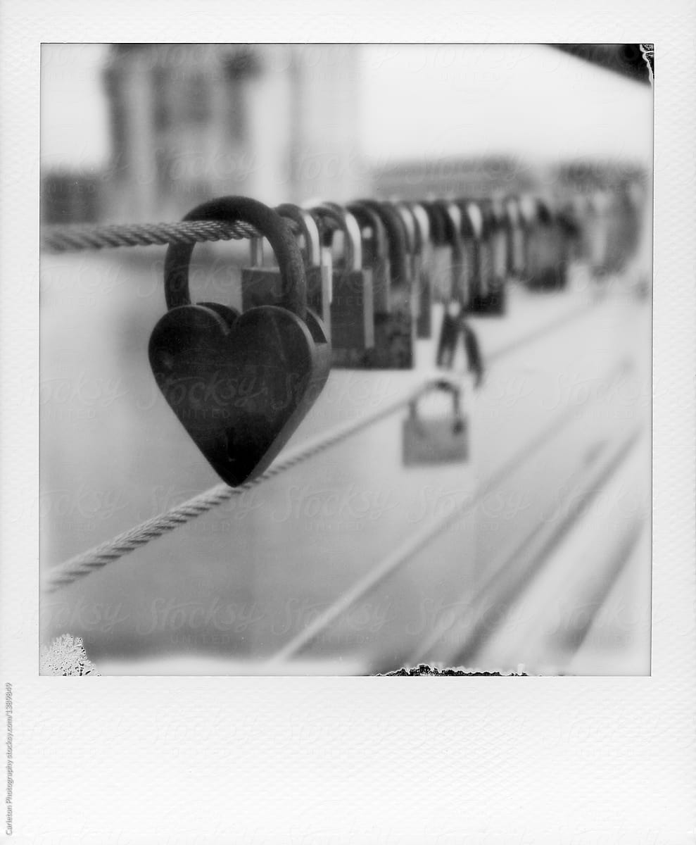 Heart shaped lock in front of other locks on cable of bridge