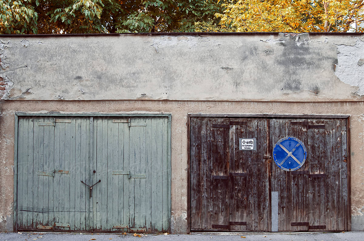 Two garage doors on the street with autumn trees behind