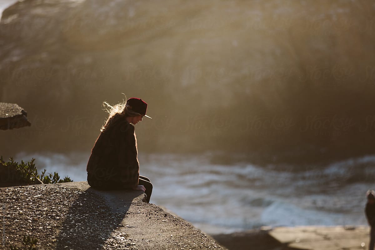 Young Woman Sitting Alone At A Vista On The California Coast At Sunset