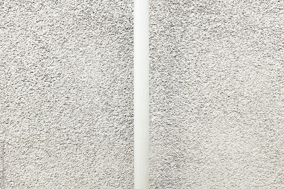 Metal pipe in front of stucco wall, close up