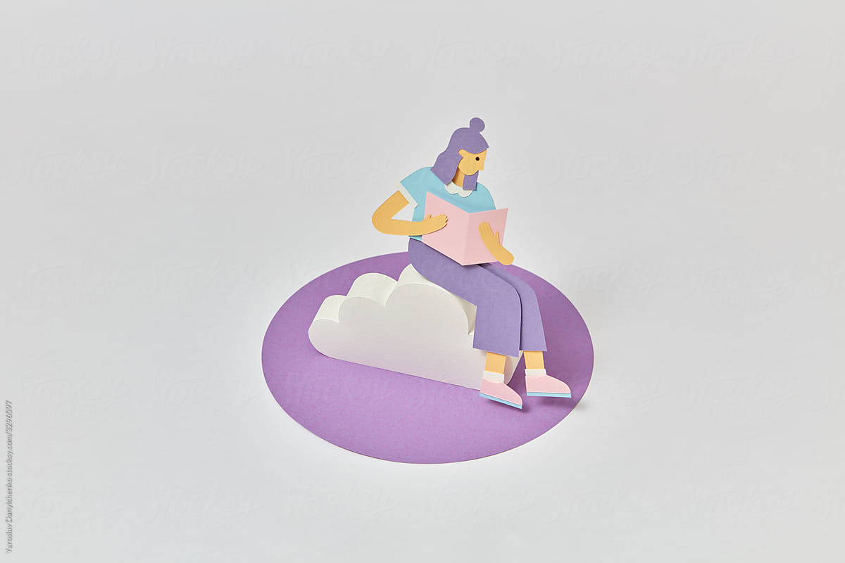 Craft girl from paper is reading book on a cloud.