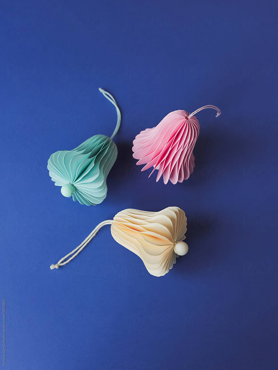 Origami bells made of colorful tissue paper placed on blue backdrop