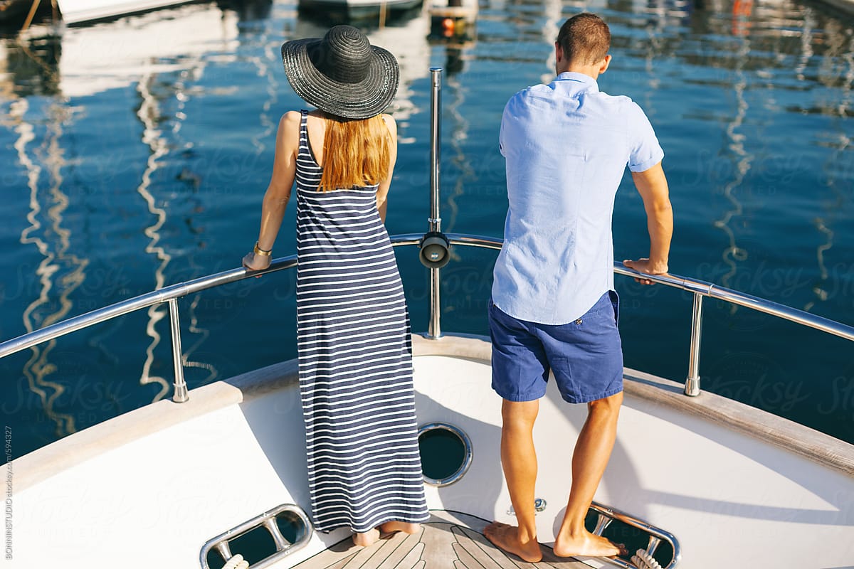 Back view of young couple looking at the dock from the yacht.
