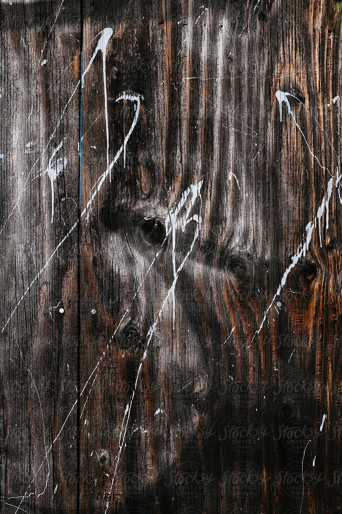Paint splattered across worn plywood wall, close up