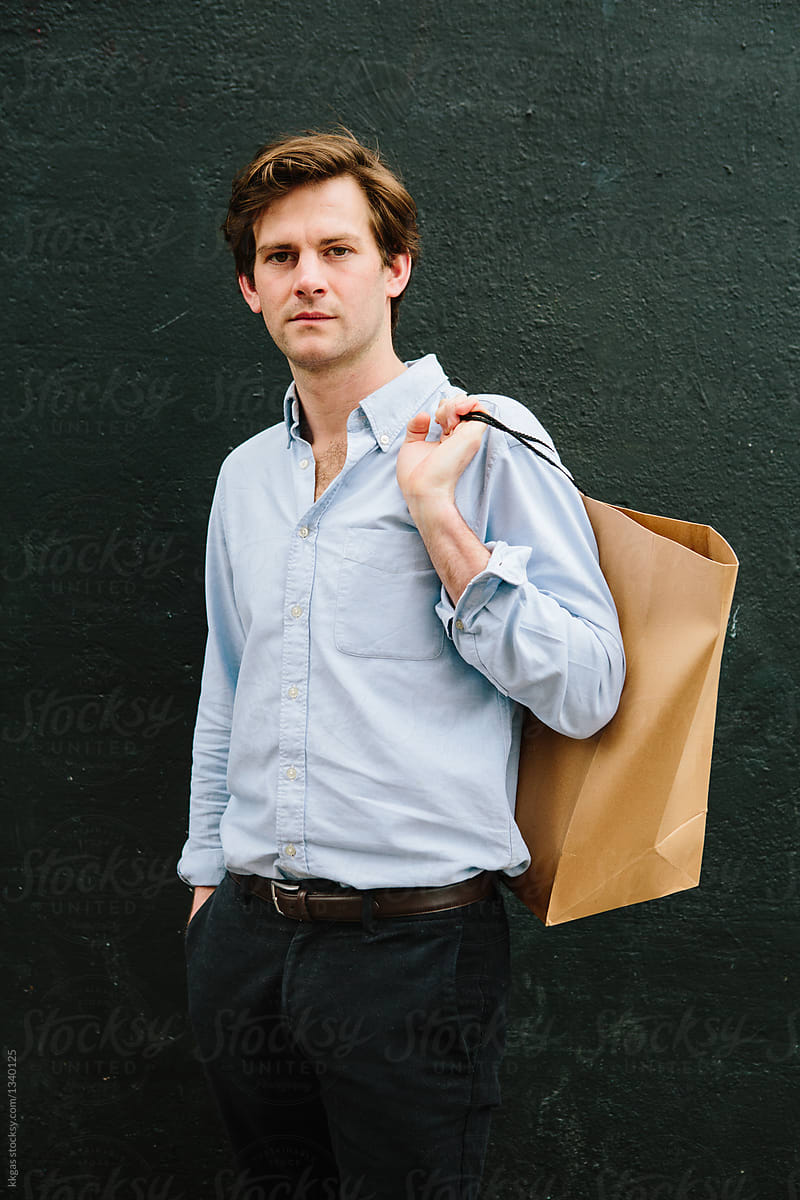 Man with shopping bag in front of black background