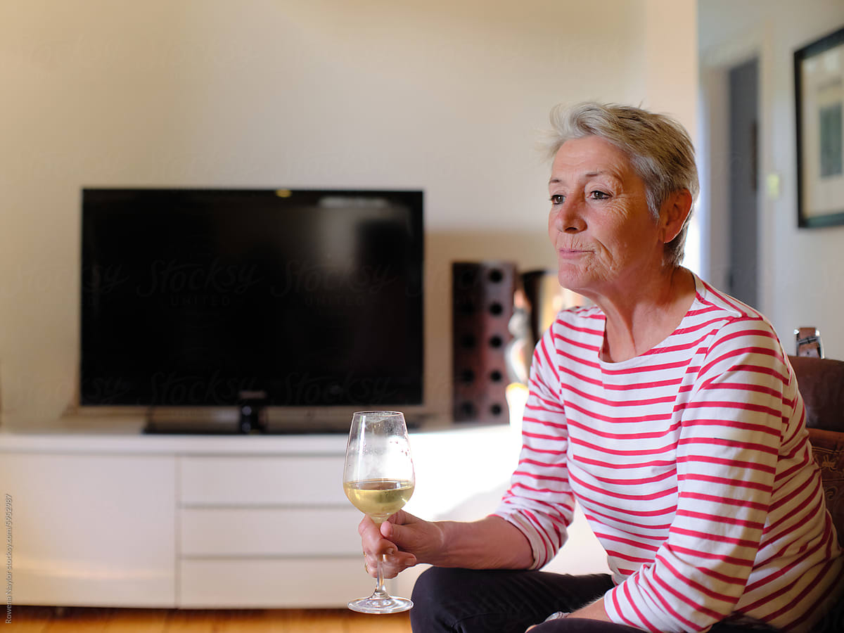Portrait of older lesbian woman at home enjoying a glass of wine