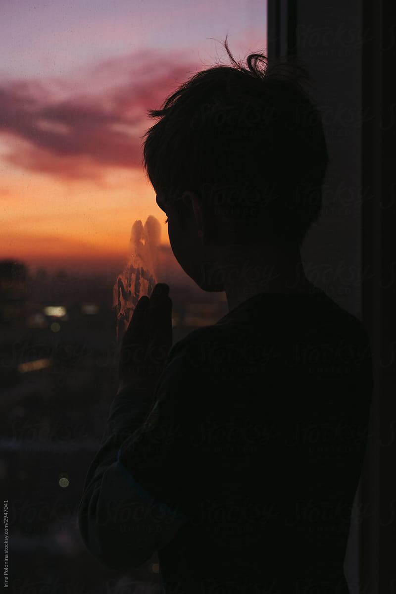 A little boy looks out the window.