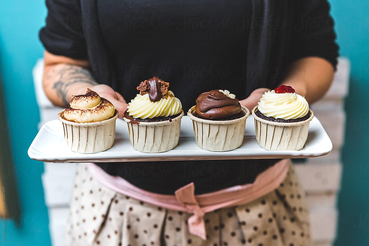 Woman Holding a Tray with Four Different Cupcakes